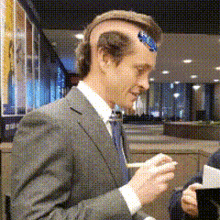 a man wearing a suit and tie has a sticker on his head