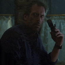 a man with a beard and a blue shirt is holding a cell phone