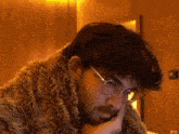 a man wearing glasses and a fur coat is looking down