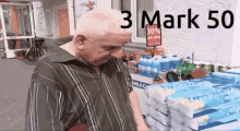 a man in a striped shirt is standing in front of a stack of toilet paper and a sign that says 3 mark 50