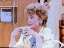 a woman with curly hair is drinking from a cup