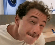 a man with curly hair is making a face with his eyes closed