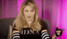 a woman is sitting in a chair wearing a black shirt and black and white striped gloves .