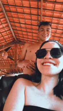 a shirtless man and a woman wearing sunglasses pose for a photo