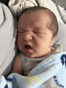 a baby is wrapped in a blue blanket with the letter g on it