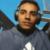 a man wearing headphones and a blue shirt with an adidas logo