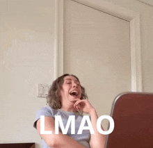 a woman is laughing in front of a laptop with the word lmao written on her face