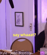 kyle jean baptiste is sitting at a table with a microphone in the background