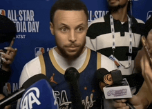 a man is talking into a microphone in front of a banner that says all star day