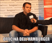 a man is sitting in front of a sign that says " sempione news "