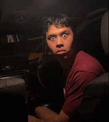 a man in a red shirt is making a funny face in a dark room
