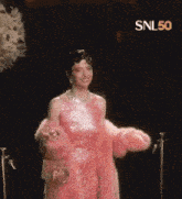 a woman in a pink dress is standing in front of a snl50 sign