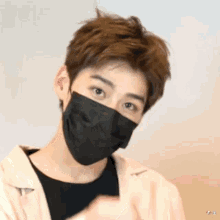 a young man wearing a black face mask is giving a thumbs up