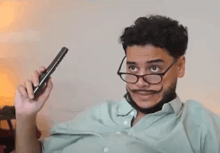 a man with a mustache and glasses is holding a remote control .