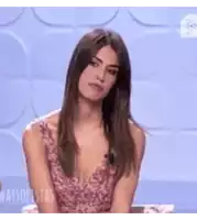 a woman in a purple dress is sitting on a couch and making a funny face .