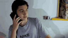 a boy wearing a nike shirt is talking on a phone
