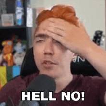 a man with red hair is holding his head in front of a microphone .