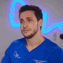 a man is smiling in front of a neon sign that says n