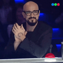 a bald man with glasses and a beard applauds