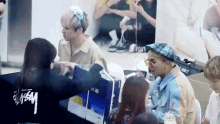 a group of people are sitting around a table with a man wearing a plaid hat and sunglasses .