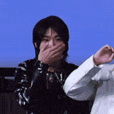 a man is covering his mouth with his hand while another man looks on