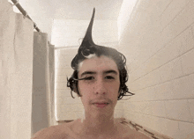 a young man taking a shower with his hair in a ponytail