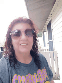 a woman wearing sunglasses and a gray shirt that says compton