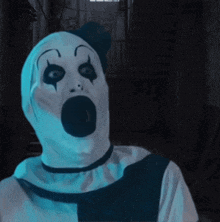 a clown with a shocked look on his face is in a dark room