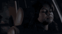 a woman is sitting in the back seat of a car at night with her eyes closed .