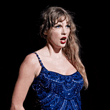 a woman in a blue sequined dress is standing in front of a black background