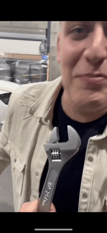 a man is holding an adjustable wrench in his hand