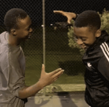 two boys are standing next to each other and one of them is wearing an adidas jacket
