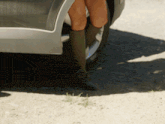 a woman wearing a pair of green boots stands next to a car