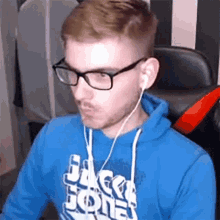 a man wearing glasses and headphones is wearing a blue hoodie that says jack jones on it .
