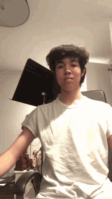 a young man in a white shirt is sitting in an office chair