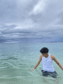 a man in a white tank top is in the ocean
