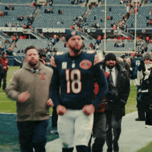 a man wearing a number 18 jersey walks on a field