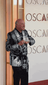 a man stands in front of a wall with the word oscar on it
