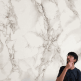 a man stands in front of a red playing card with a circular pattern