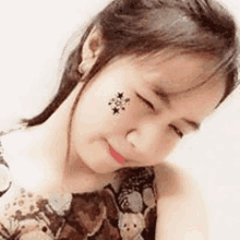 a close up of a woman 's face with a tattoo of stars on it .