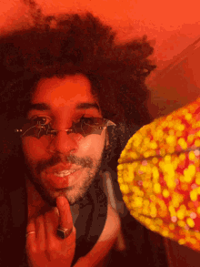 a man with a ring on his finger wears a pair of bat shaped sunglasses