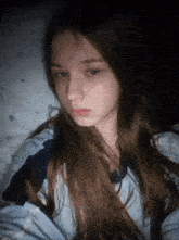 a girl with long hair is laying on a bed and looking at the camera