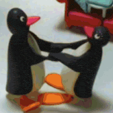 two penguins are dancing in a circle with a red couch in the background