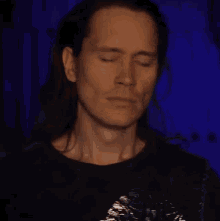 a man with long hair has his eyes closed