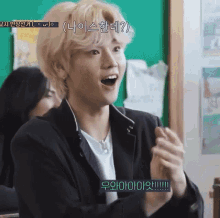 a young man is clapping his hands in a classroom while wearing headphones .