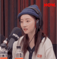 a woman wearing headphones and a blue hat is sitting in front of a microphone .