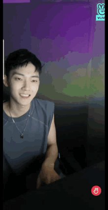 a young man is sitting in front of a purple wall with a vlive logo on it