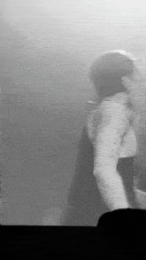 a black and white photo of a man standing in front of a crowd .