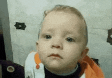 a baby is making a funny face while looking at the camera .