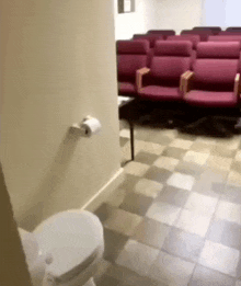 a bathroom with a toilet and a row of chairs